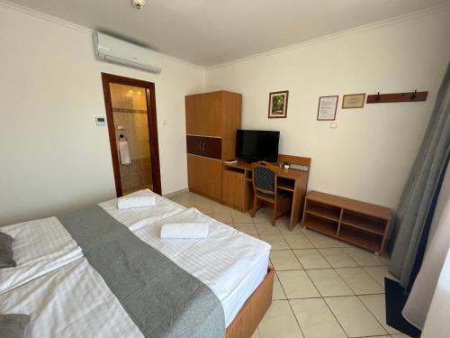 a bedroom with a bed and a desk with a computer at Hegyalja Fogadó in Sárospatak