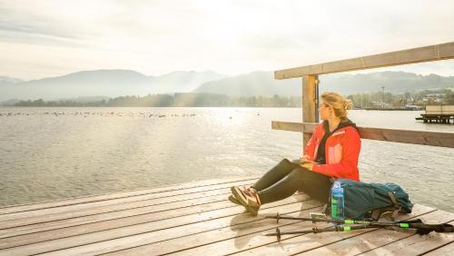 a woman sitting on a dock next to the water at Apartmenthotel 's Mitterndorf in Traunkirchen