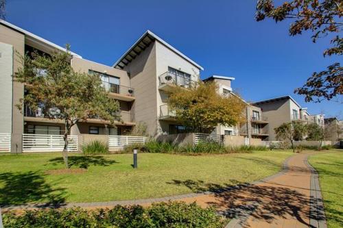 un gran edificio de apartamentos con césped delante en The Paddocks Dainfern, en Fourways