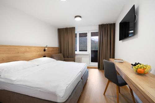 a hotel room with a bed and a desk and a television at Wellness Hotel Repiska in Demanovska Dolina