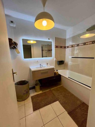une salle de bain avec un lavabo, un miroir et une baignoire dans l'établissement Cocon aux portes de Paris - free parking - métro 7 & 14, à Villejuif