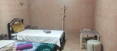 a room with two beds and a table and a cross at Auberge Restaurant TISSILI " Oasis de Fint" in Fint