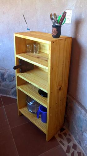 a wooden shelf with a pot of kitchen utensils at Las Ranas in Tilcara