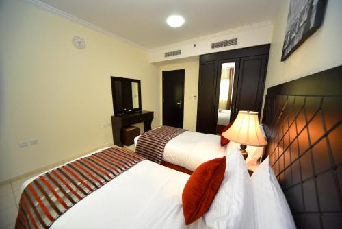 a hotel room with two beds and a television at Alain Hotel Ajman in Ajman 