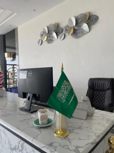 a desk with a computer with a cup and a flag at نوفل للشقق المخدومة in Ad Dawādimī