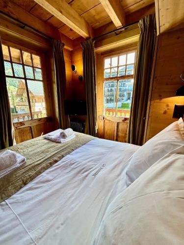 a large bed in a room with two windows at Unique, High-Design 6 Bedrooms Chalet in Villars Centre in Ollon