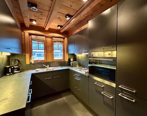 a kitchen with stainless steel appliances and wooden ceilings at Unique, High-Design 6 Bedrooms Chalet in Villars Centre in Ollon