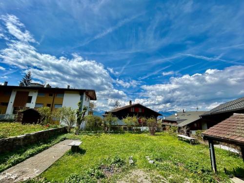 a green yard with houses and a blue sky with clouds at Unique, High-Design 6 Bedrooms Chalet in Villars Centre in Ollon