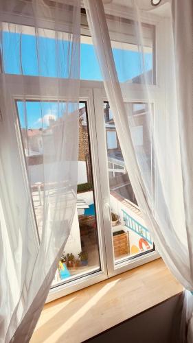 - une fenêtre avec des rideaux blancs et une vue sur l'océan dans l'établissement VILLA JULIETTE, à Dunkerque