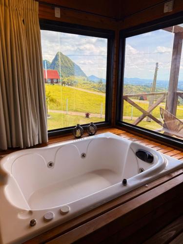 a large white bath tub in a room with a window at Cabana Jardim Encantado in Barracão