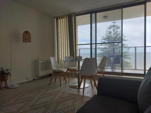a living room with a table and chairs and a large window at Seaview Escape Glenelg in Glenelg