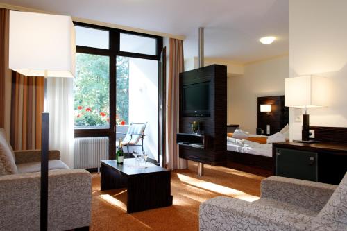 a living room with a couch and a tv and a bed at Hotel Hirschen in Glottertal