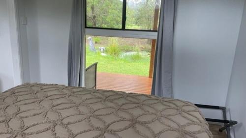a bedroom with a bed and a large window at Private country 1 Bedroom Cabin in Landsborough