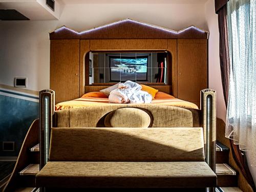 a bed with a headboard with a person laying on it at Hotel Butterfly in Torre del Lago Puccini