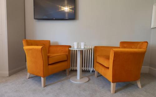 two orange chairs and a table with a tv at Heacham Manor Hotel in Hunstanton