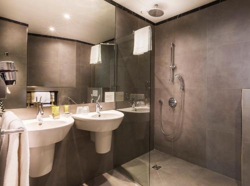 a bathroom with two sinks and a shower at Hôtel Albe Saint Michel in Paris