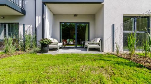 a house with a patio with two chairs on a lawn at InTheMiddle in Ostróda