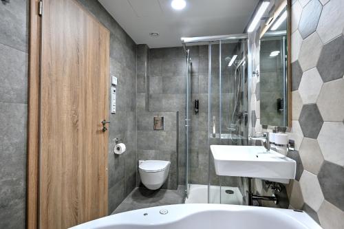 a bathroom with a tub and a sink and a toilet at Wellness Hotel Fénix in Liberec