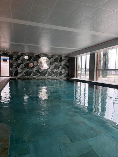 a large swimming pool with blue water in a building at Best Western Aquakub in Aix-les-Bains