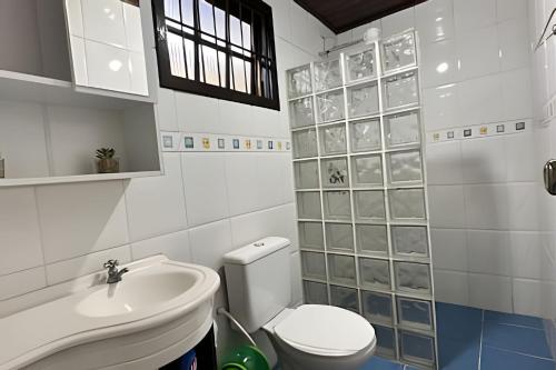 a white bathroom with a toilet and a sink at Linda Casa em Juquehy - SP (3) in São Sebastião