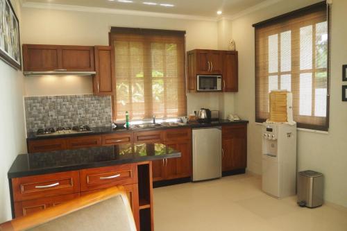 a kitchen with wooden cabinets and a white refrigerator at The Gecho Inn Country in Jepara