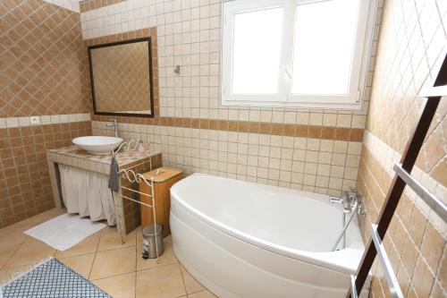 une salle de bain avec une baignoire blanche et un lavabo dans l'établissement Saint Cyprien Jolie villa climatisee avec piscine et jardin, à Saint-Cyprien