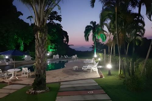 a resort with a pool and palm trees at night at Linda casa em Boiçucanga (Litoral Norte SP) in Boicucanga