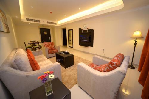 a living room with two couches and a tv at Alain Hotel Ajman in Ajman 