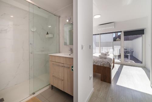 ein Badezimmer mit Dusche, Waschbecken und Spiegel in der Unterkunft Casinha da Rita by Home Sweet Home Aveiro in Aveiro