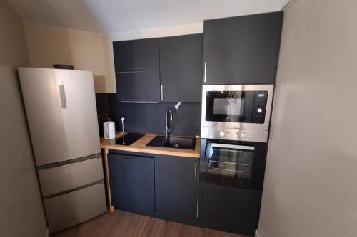 La cuisine est équipée de placards noirs, d'un évier et d'un réfrigérateur. dans l'établissement T2 apartment in residence with pool, à Le Touquet-Paris-Plage