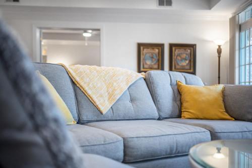 a blue couch with yellow pillows in a living room at The Clubhouse Hideaway - The Greenview Den in Chapel Hill
