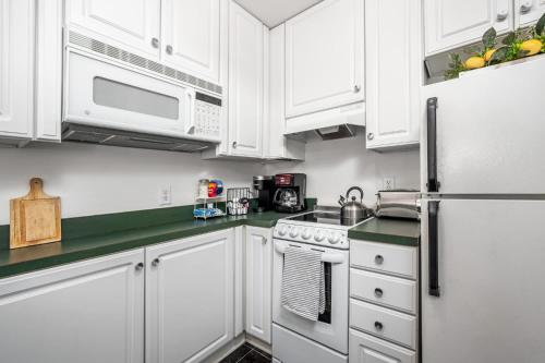 a kitchen with white cabinets and a white refrigerator at The Clubhouse Hideaway - The Greenview Den in Chapel Hill