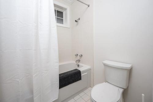 a white bathroom with a toilet and a shower at The Clubhouse Hideaway - The Greenview Den in Chapel Hill