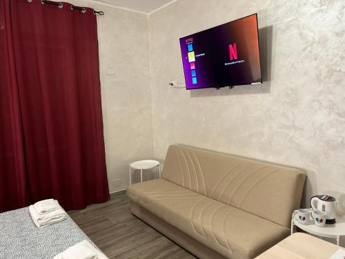 a living room with a couch and a television on the wall at Guest House Il Faraone in Fiumicino