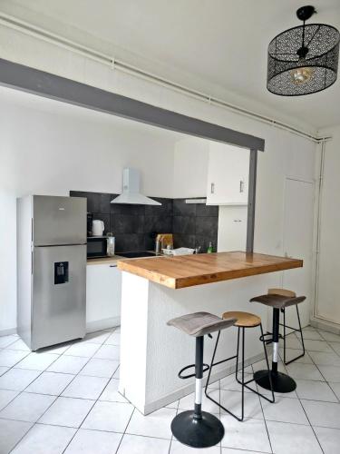 une cuisine avec un comptoir et deux tabourets de bar dans l'établissement Tour Nord - T3 entre Bastide et Cité medievale, à Carcassonne