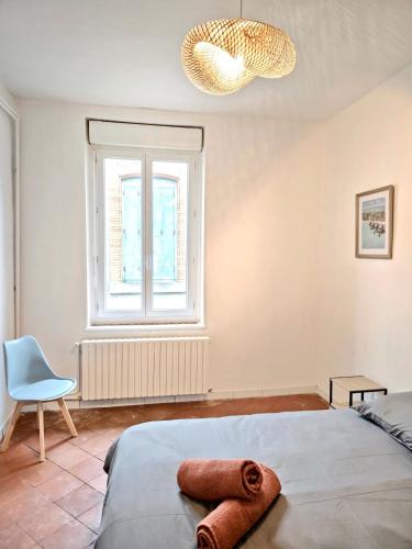 une chambre avec un lit, une fenêtre et une chaise dans l'établissement Tour Nord - T3 entre Bastide et Cité medievale, à Carcassonne