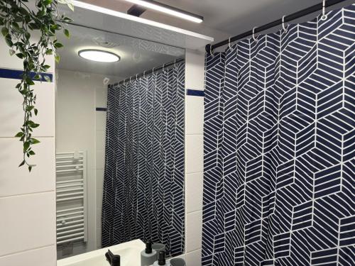 La salle de bains est pourvue d'un rideau de douche noir et blanc. dans l'établissement Idéal en famille ou entre amis - Grand T4, vue degagée, parking privé, proche centre-ville, metro Borderouge à 5min, à Toulouse