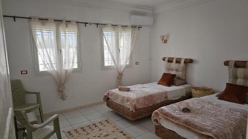 a bedroom with two beds and two windows at Villa Narjess in Taguermess