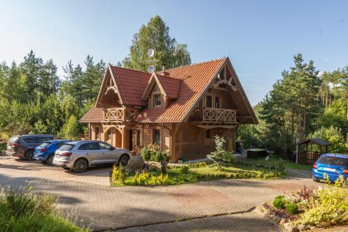 a house with cars parked in a parking lot at Leśny Dworek Podjazy in Podjazy