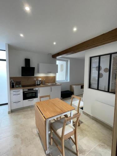 une cuisine avec une table et des chaises dans une pièce dans l'établissement Appartement calme et chaleureux, à Saint-Germain-du-Bois