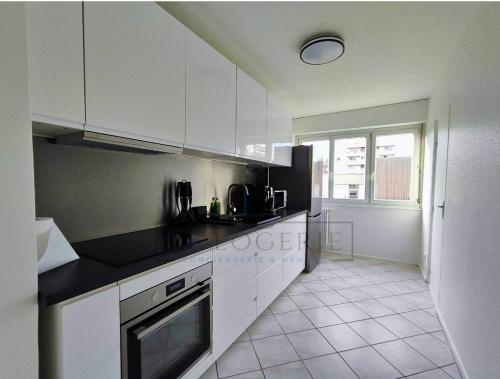 une cuisine avec des armoires blanches et un sol carrelé dans l'établissement #Junior - Mulhouse centre ville, à Mulhouse