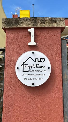 a sign on the side of a red building at Virgy’s House in Sestu