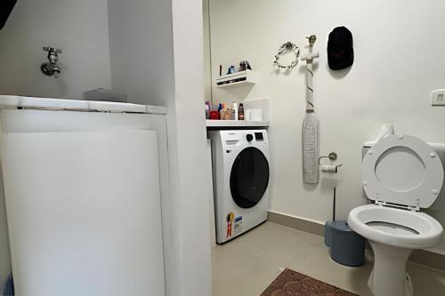 a bathroom with a toilet and a washing machine at Lindo Flat na Praia Barra do Una in Barra do Una