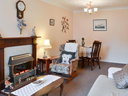 a living room with a fireplace and a chair and a table at Cosy Corner in Bessingby