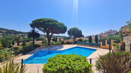 - une piscine dans une cour avec des arbres et des buissons dans l'établissement Apartbleuazur - Bel appartement rénové piscine & vue mer, à Cavalaire-sur-Mer