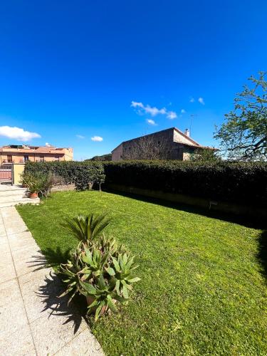 a grassy yard with a hedge and a sidewalk at Appartamento tra il borgo e il lago in Anguillara Sabazia
