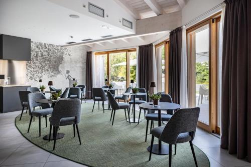 a dining room with tables and chairs and windows at Blu Hotel Natura & Spa - Adults Only in Folgaria