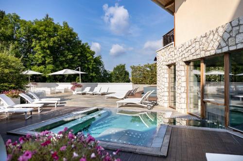 a swimming pool with lounge chairs and a house at Blu Hotel Natura & Spa - Adults Only in Folgaria