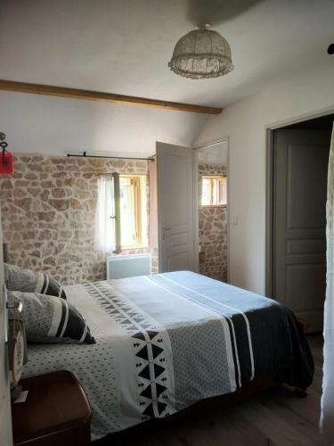 une chambre avec un lit et un mur en pierre dans l'établissement Gîte rural au Bois des Riots, à Montillot