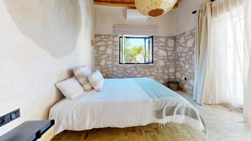 a bedroom with a bed with a stone wall at La Pausa du Douar in Essaouira